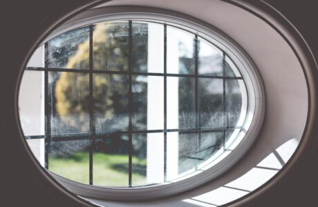 oval shaped wooden casement window with leaded glass
